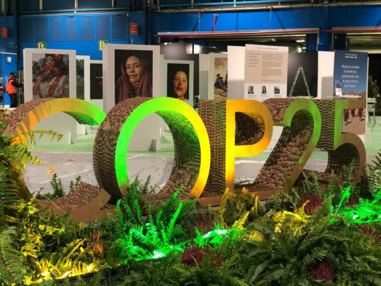 De fondo parte de la muestra fotográfica “Mujeres Rurales en América: sembrando hoy la agricultura del futuro”, que presentó el IICA en la COP25 en Madrid.