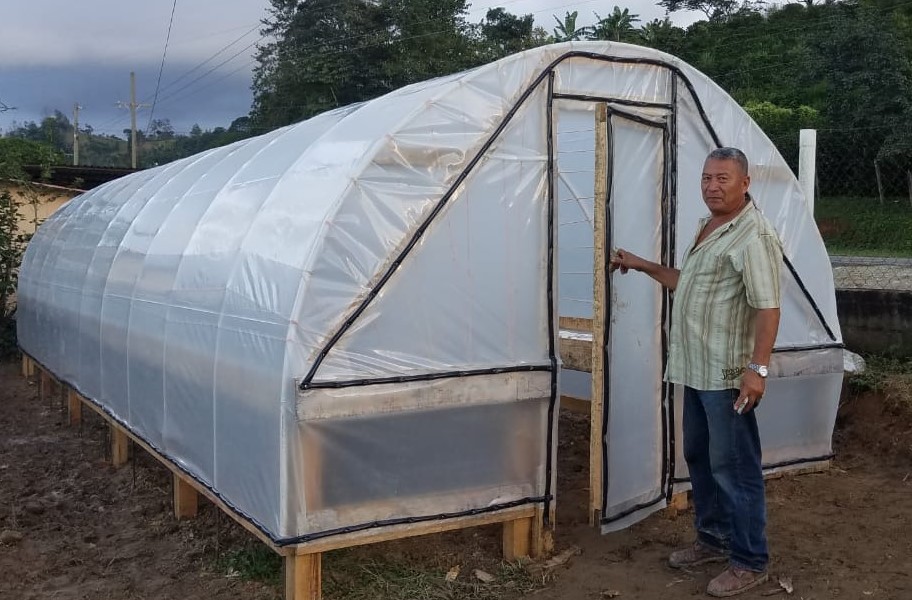 Abdon Seney Arqueta, de la caja rural Familias Unidas en La Paz, Honduras, frente a su secadora solar