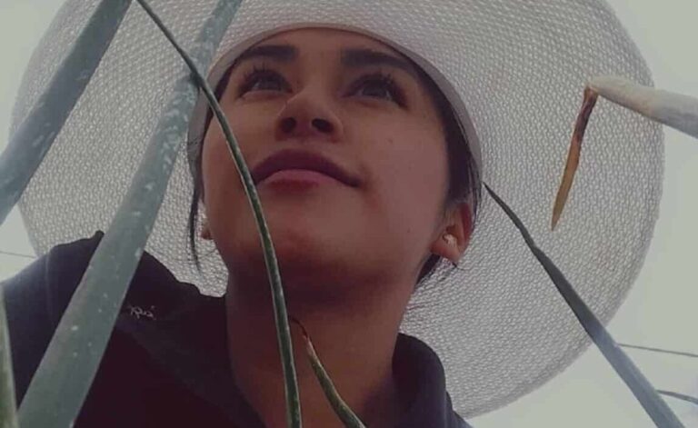 Imagen inspiradora de una joven líder rural entre hojas verdes, con sombrero blanco que simboliza trabajo y protección. Ideal para contenidos sobre empoderamiento femenino, liderazgo agrícola y sostenibilidad en zonas rurales.
