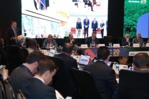 Sesión plenaria de la Conferencia de Ministros de Agricultura de las Américas 2025 en Brasilia, con delegaciones oficiales reunidas en torno a una mesa de trabajo equipada con computadoras portátiles y material institucional del IICA. En la pantalla de fondo se proyectan imágenes de autoridades y mensajes clave del encuentro, que aborda temas como seguridad alimentaria, innovación agrícola y cooperación regional.