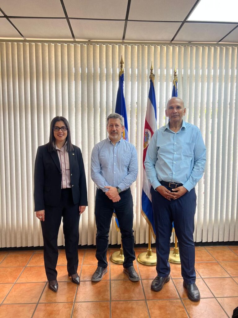 : Reunión de representantes del sector lechero frente a banderas institucionales en Costa Rica, en el marco de iniciativas para impulsar la sostenibilidad de la lechería en América Latina y el Caribe, con participación de organismos regionales como IICA y FEPALE.